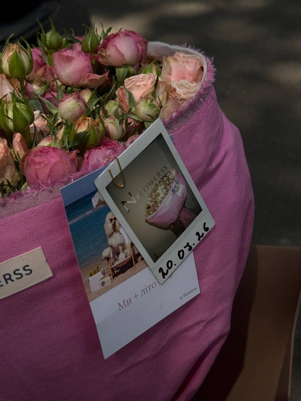 Polaroid-знімок із підписаною датою, прикріплений до рожевого тканинного пакування букета